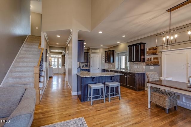 kitchen featuring decorative backsplash, dark brown cabinets, decorative light fixtures, and light hardwood / wood-style flooring