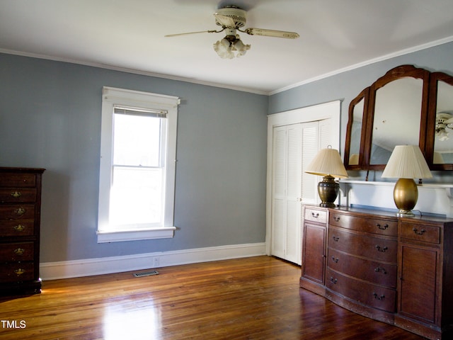 bedroom featuring ceiling fan, a closet, dark wood-type flooring, and ornamental molding