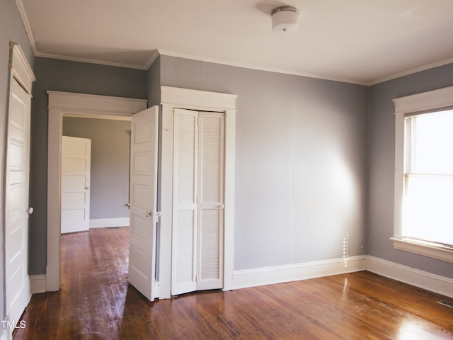 unfurnished bedroom featuring dark hardwood / wood-style flooring, a closet, and ornamental molding