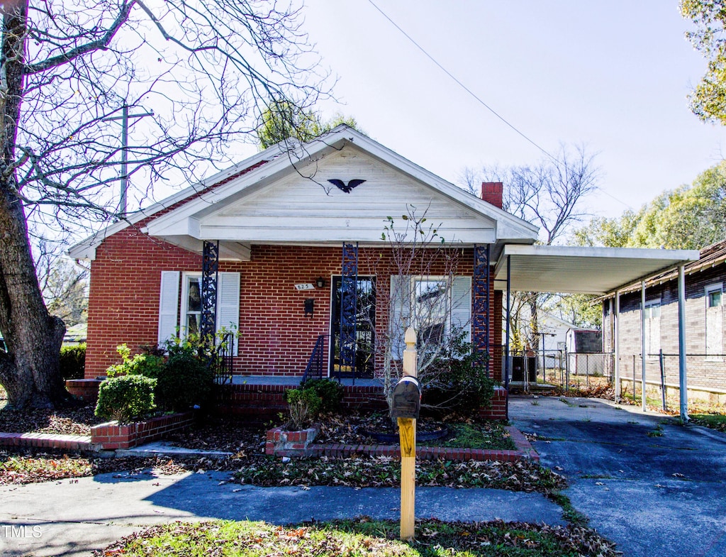 823 E Holly St, Rocky Mount, NC 27801 - view of front of house with driveway, a carport, brick siding, a porch, and a chimney