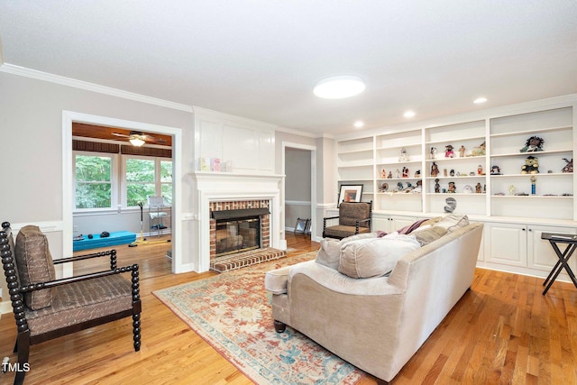 living room with ornamental molding, a brick fireplace, and light hardwood / wood-style floors