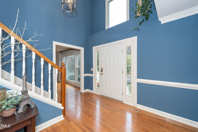 foyer featuring crown molding, wood-type flooring, a high ceiling, and plenty of natural light