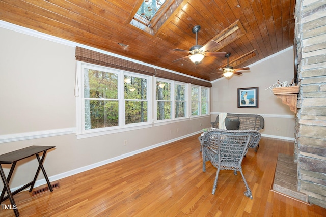 living area featuring wooden ceiling, ornamental molding, hardwood / wood-style flooring, ceiling fan, and vaulted ceiling with skylight