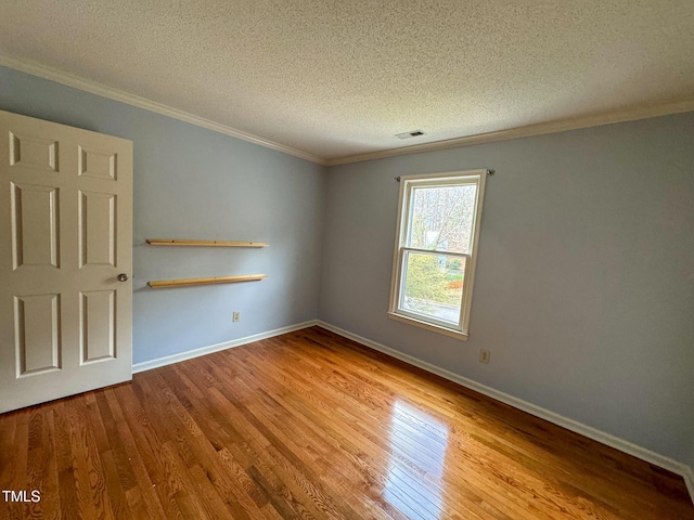 spare room featuring ornamental molding, a textured ceiling, and light wood-type flooring