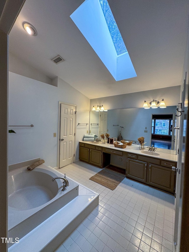 bathroom with vanity, vaulted ceiling with skylight, a bathing tub, and tile patterned flooring