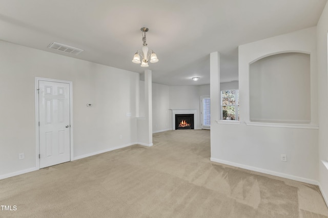 unfurnished living room featuring light carpet and a notable chandelier