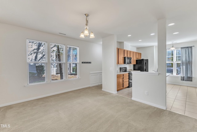 kitchen featuring black appliances, plenty of natural light, light colored carpet, and hanging light fixtures