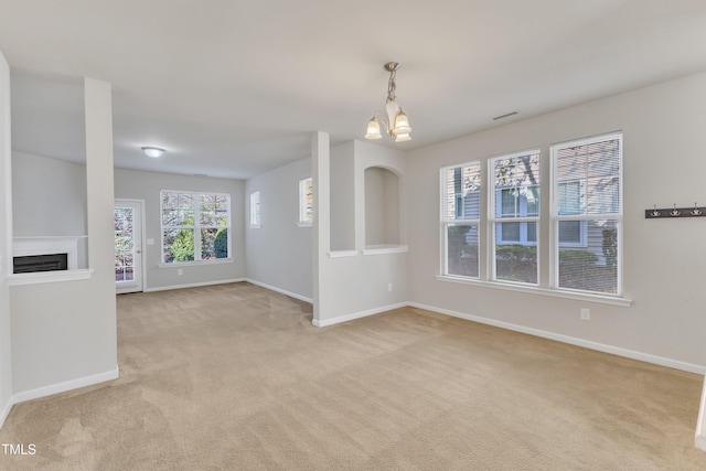 unfurnished living room with light carpet and an inviting chandelier