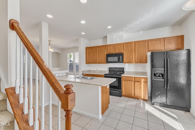 kitchen featuring black appliances, light tile patterned floors, sink, and an island with sink