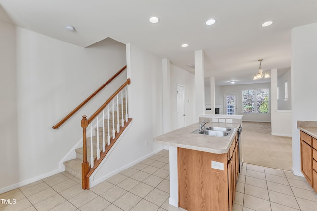 kitchen with light tile patterned flooring, decorative light fixtures, an island with sink, and sink