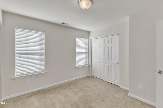 unfurnished bedroom with light carpet and a closet