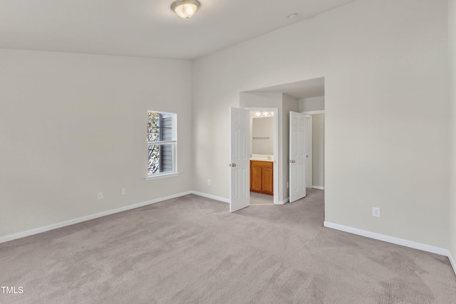 unfurnished bedroom featuring ensuite bath and light carpet