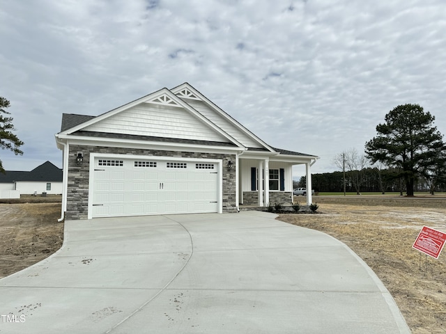 view of front of house featuring a garage, stone siding, covered porch, and concrete driveway