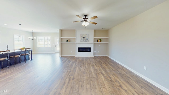 1407 Stoney Creek Church Rd, Goldsboro, NC 27534 - living room with wood finished floors, a ceiling fan, baseboards, a tiled fireplace, and a chandelier