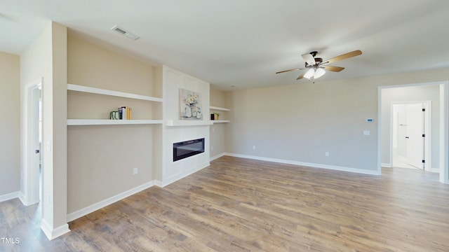 1407 Stoney Creek Church Rd, Goldsboro, NC 27534 - unfurnished living room with ceiling fan, light wood-type flooring, a glass covered fireplace, baseboards, and built in features