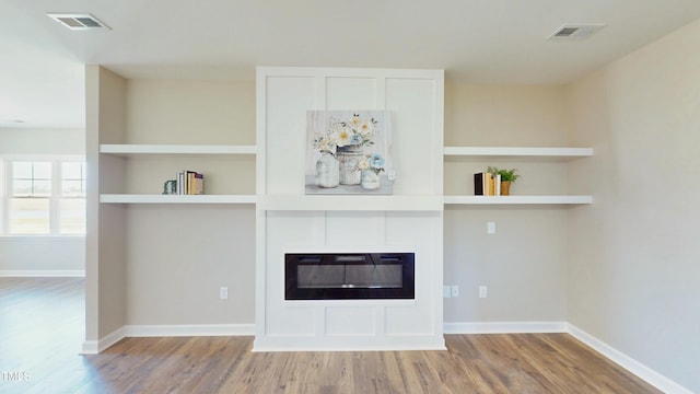 1407 Stoney Creek Church Rd, Goldsboro, NC 27534 - unfurnished living room featuring a glass covered fireplace, wood finished floors, and baseboards