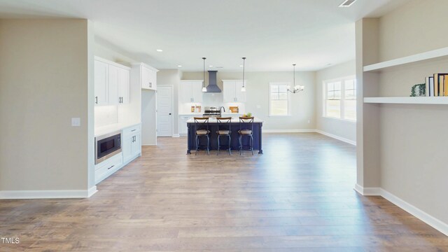 1407 Stoney Creek Church Rd, Goldsboro, NC 27534 - kitchen with extractor fan, a chandelier, light wood-type flooring, built in microwave, and white cabinets
