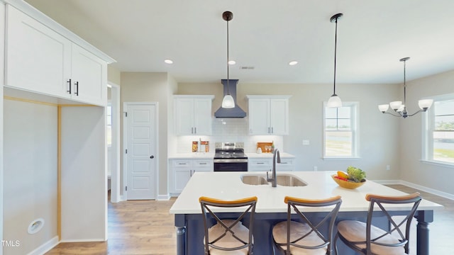 1407 Stoney Creek Church Rd, Goldsboro, NC 27534 - kitchen with stainless steel range with electric cooktop, wall chimney range hood, a sink, light countertops, and white cabinetry