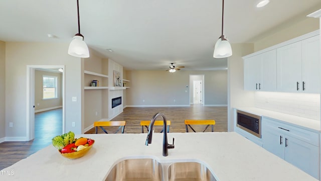 1407 Stoney Creek Church Rd, Goldsboro, NC 27534 - kitchen with a sink, built in microwave, a glass covered fireplace, wood finished floors, and decorative light fixtures
