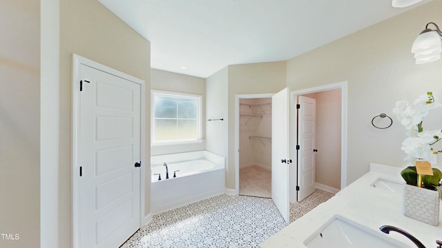 1407 Stoney Creek Church Rd, Goldsboro, NC 27534 - bathroom featuring a sink, a garden tub, speckle patterned floor, baseboards, and a walk in closet