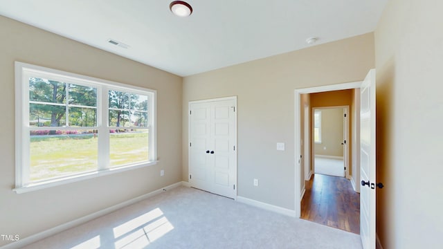 1407 Stoney Creek Church Rd, Goldsboro, NC 27534 - unfurnished bedroom featuring multiple windows, baseboards, light colored carpet, and a closet