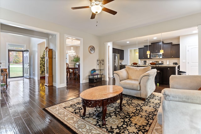 living room featuring dark wood-type flooring and ceiling fan with notable chandelier