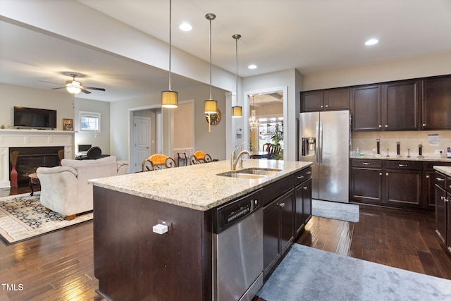 kitchen featuring sink, dark brown cabinets, stainless steel appliances, a center island with sink, and decorative light fixtures