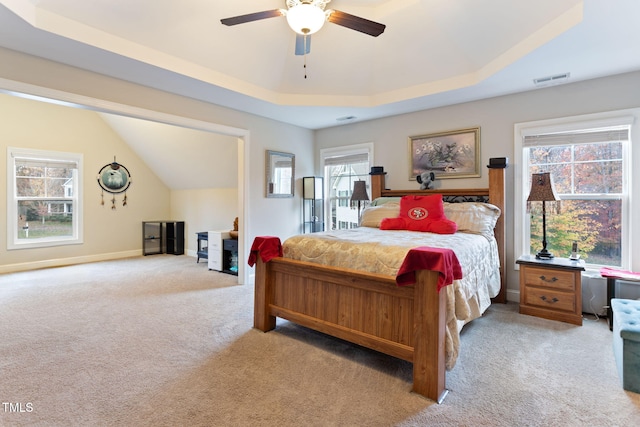 carpeted bedroom featuring a tray ceiling and ceiling fan