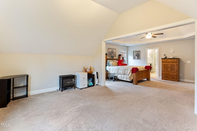 bedroom featuring ceiling fan, vaulted ceiling, light carpet, and a wood stove