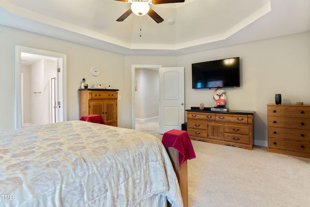 bedroom featuring a raised ceiling, light colored carpet, and ceiling fan