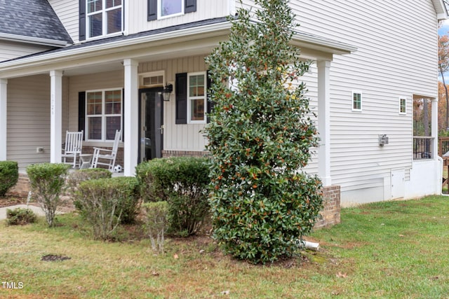 doorway to property featuring a porch and a yard