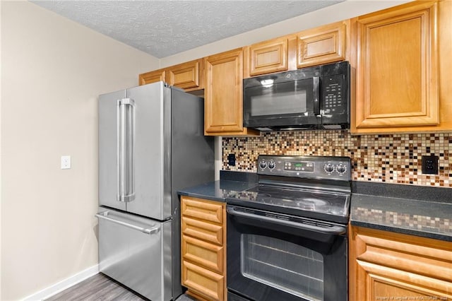 kitchen with dark stone counters, decorative backsplash, black appliances, and light hardwood / wood-style floors