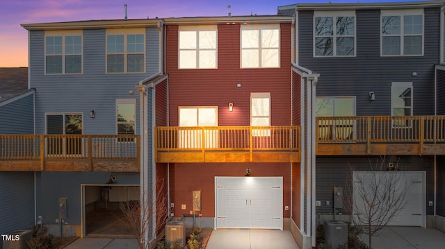 back house at dusk featuring a balcony and central air condition unit