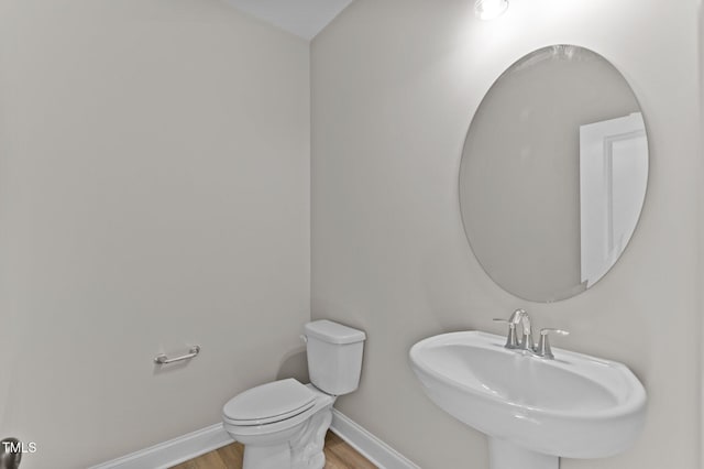 bathroom with wood-type flooring, toilet, and sink