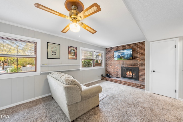 carpeted living room featuring a fireplace, a textured ceiling, ceiling fan, and crown molding