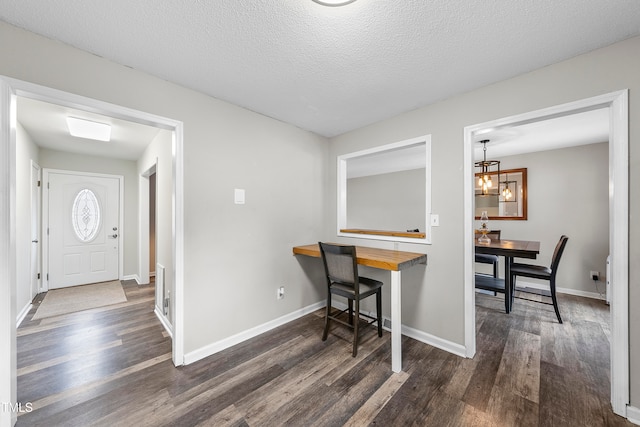 office with a textured ceiling, dark wood-type flooring, and an inviting chandelier