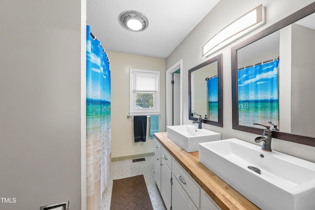 bathroom with a shower with shower curtain, vanity, and a textured ceiling