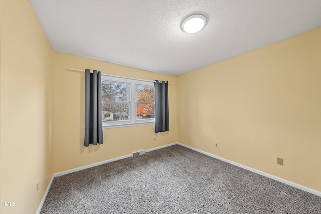 empty room with carpet floors and a textured ceiling