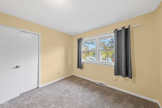 unfurnished bedroom with a textured ceiling, carpet floors, and a closet