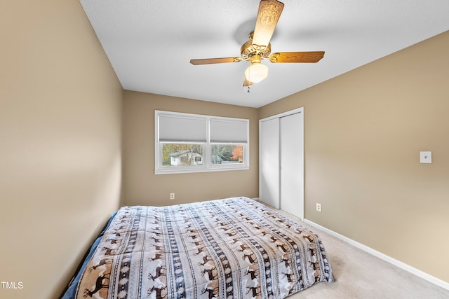 bedroom featuring ceiling fan, a closet, light colored carpet, and a textured ceiling