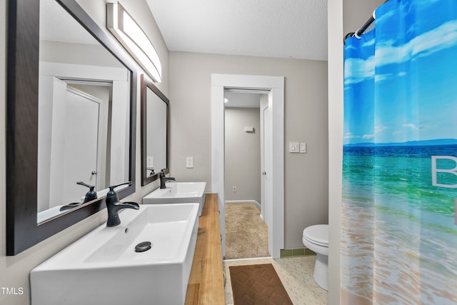 bathroom with hardwood / wood-style floors, vanity, toilet, and a textured ceiling