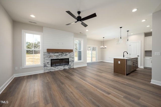 unfurnished living room featuring a sink, baseboards, dark wood finished floors, and a wealth of natural light