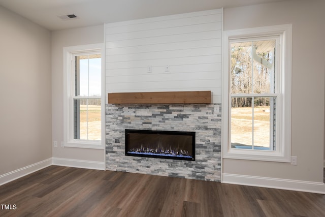 unfurnished living room with visible vents, a fireplace, baseboards, and dark wood finished floors