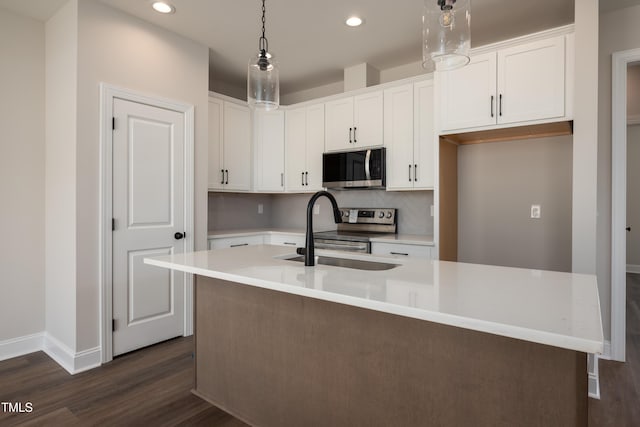 kitchen featuring stainless steel appliances, white cabinets, a sink, and an island with sink