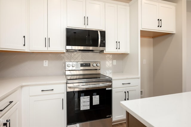 kitchen with light stone countertops, white cabinetry, appliances with stainless steel finishes, and backsplash