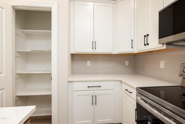 kitchen with tasteful backsplash, appliances with stainless steel finishes, light countertops, white cabinetry, and open shelves