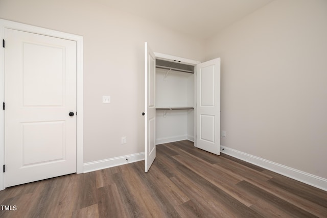 unfurnished bedroom featuring dark wood-style floors, a closet, and baseboards