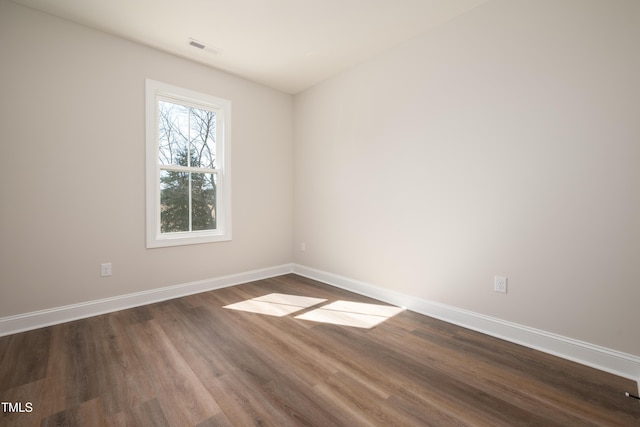 unfurnished room with dark wood-type flooring, visible vents, and baseboards