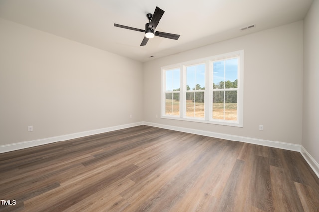 spare room with ceiling fan, dark wood finished floors, visible vents, and baseboards