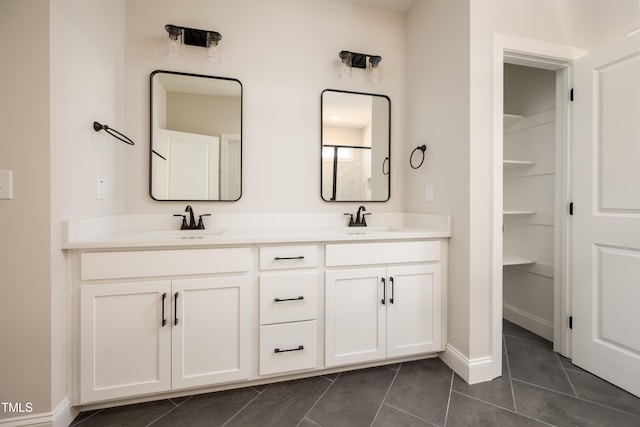 bathroom with baseboards, double vanity, a sink, and tile patterned floors